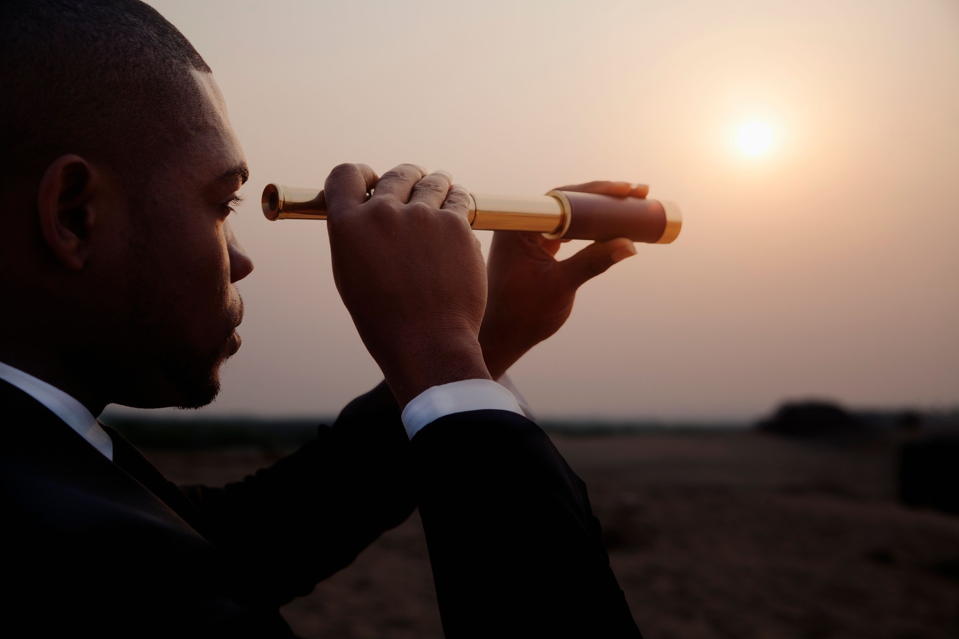 Businessman looking through spyglass in middle of the desert